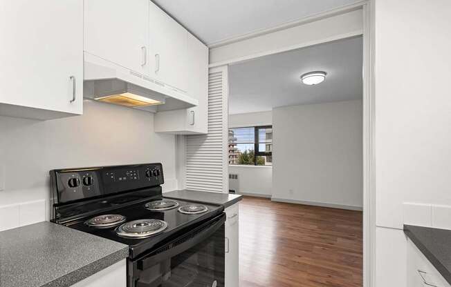 an empty kitchen with white cabinets and a black stove