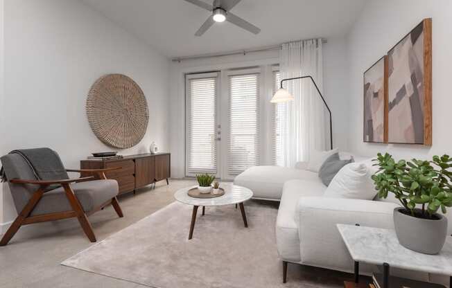 a living room with white furniture and a ceiling fan
