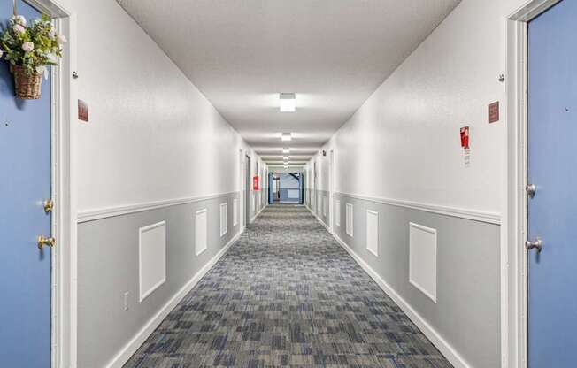 A long hallway with blue doors and white walls.