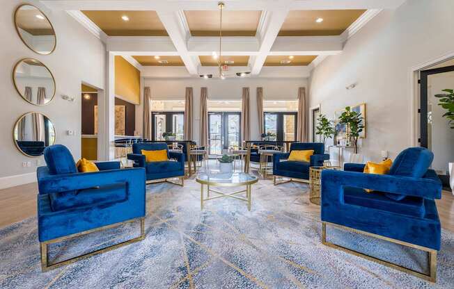 A living room with blue velvet chairs and a patterned rug.