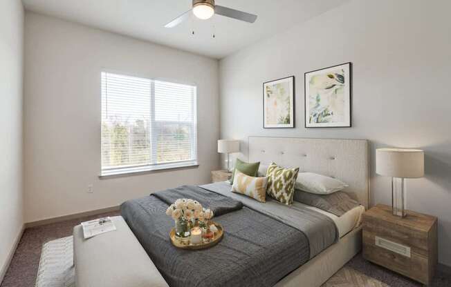 A bedroom with a large bed, a ceiling fan, and two framed pictures on the wall.