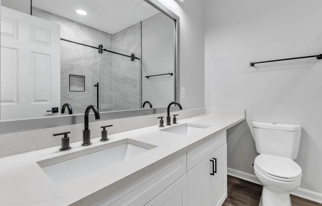 A white bathroom with a toilet, sink, and mirror.