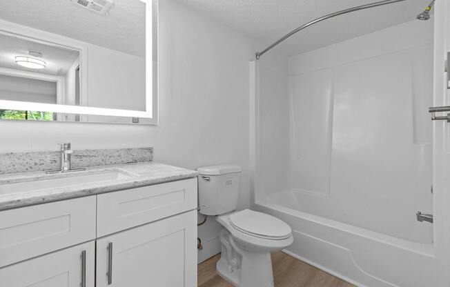 A white bathroom with a toilet, sink, and bathtub.