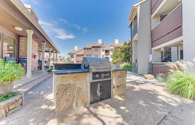 A stone fireplace is in the middle of a gravel courtyard.