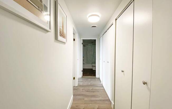 A long hallway with white walls and wood flooring.