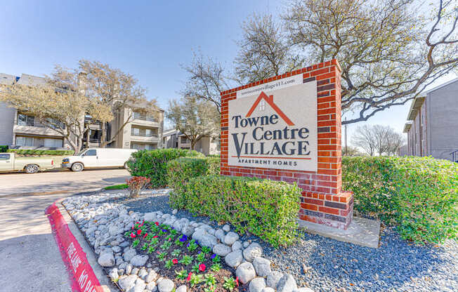 A sign for Towne Centre Village Apartment Homes is displayed in front of a landscaped area.