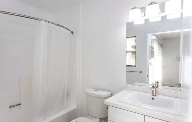 A white bathroom with a toilet, sink, and shower.