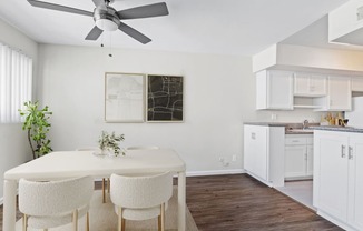 a kitchen and dining room with white cabinets and a ceiling fan