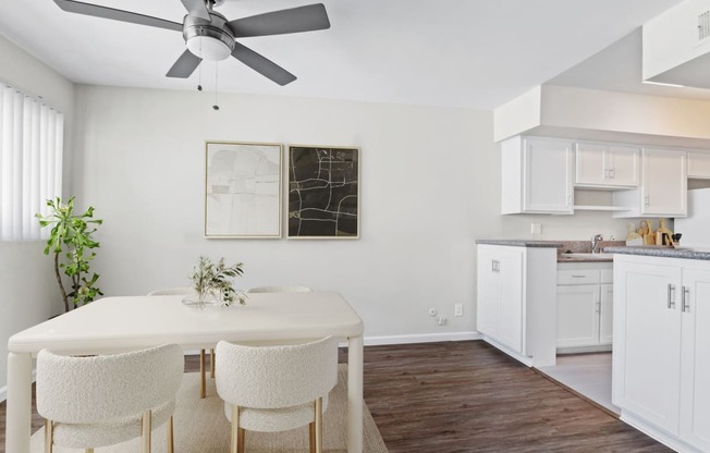 a kitchen and dining room with white cabinets and a ceiling fan