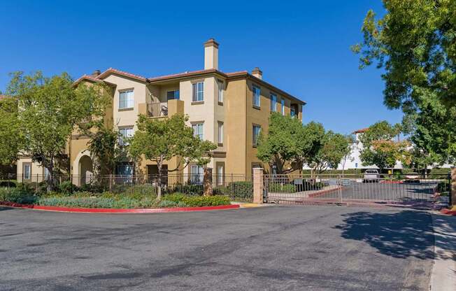 A large beige building with a red fence and gate in front.