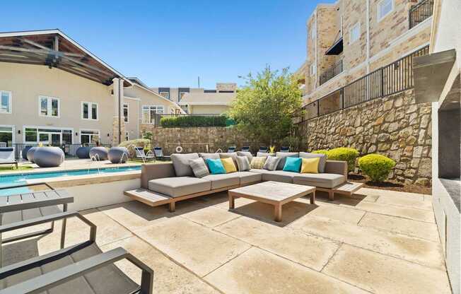 A patio with a couch and chairs overlooking a pool.