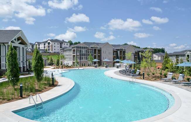 A large outdoor swimming pool surrounded by lounge chairs and umbrellas.