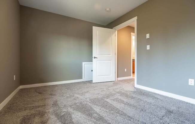 A room with a carpeted floor and a white door.
