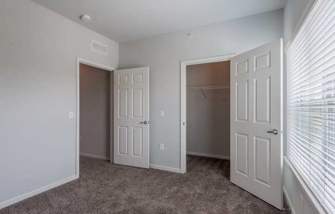 an empty bedroom with two doors and a closet