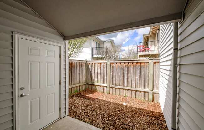 a white door opens to a small patio with a wooden fence