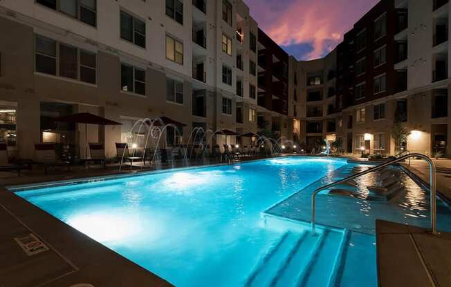 a swimming pool at night in front of an apartment building