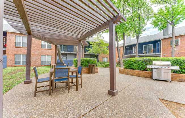 A patio with a table and chairs under a wooden roof.