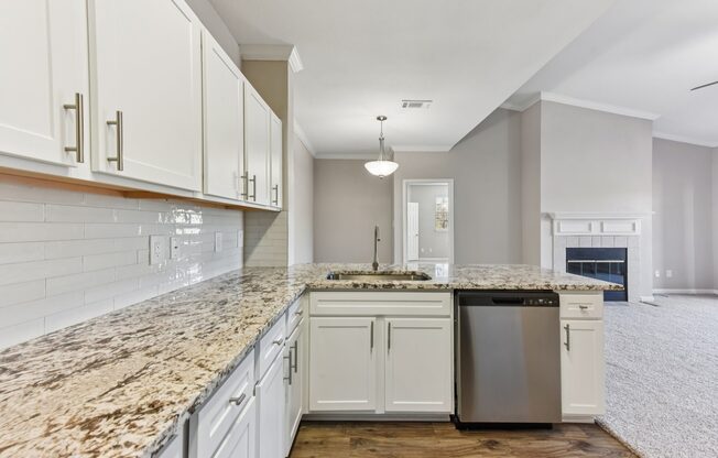 A kitchen with granite countertops and white cabinets.