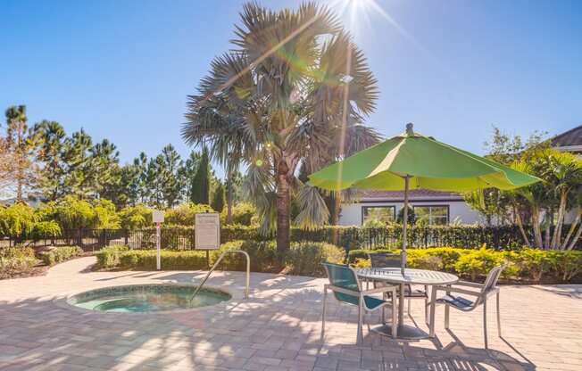 a patio with a hot tub and a table with an umbrella