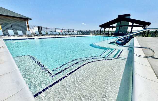 A large swimming pool with a diving board and lounge chairs.