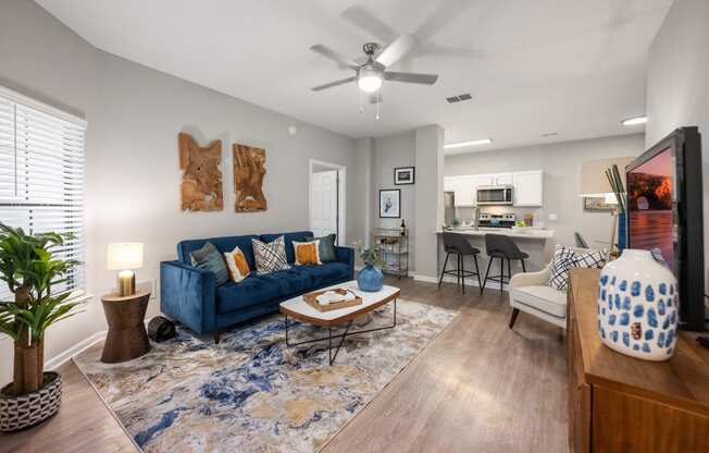 an open living room and kitchen with a blue couch and a ceiling fan