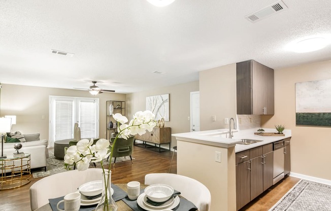 the living room and kitchen of an apartment with a dining table and chairs at Crossgates Apartment Homes, Starkville