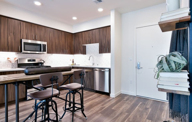 a kitchen with a bar and stools in front of a counter with three chairs