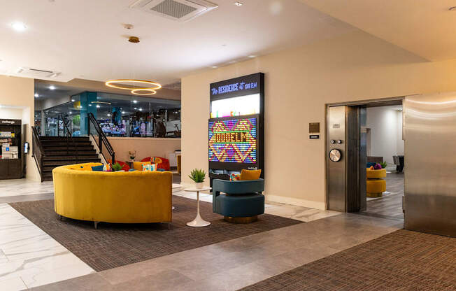 a lobby of a hotel with a yellow couch and chairs and a vending machine