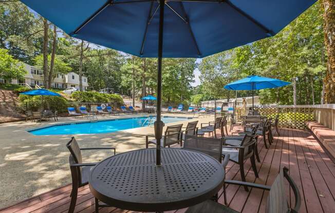 a patio with tables and umbrellas and a swimming pool