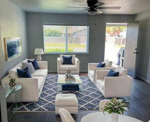 A living room with white furniture and a ceiling fan.