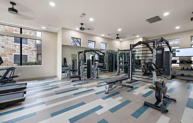 a gym with weights and cardio equipment and a large window
