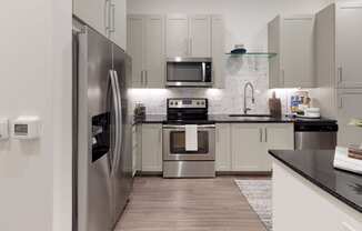 Kitchen with wood cabinets and stainless steel appliances with undermount sink and gooseneck faucet.