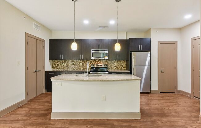 a kitchen with a large island and a stainless steel refrigerator at Lakeline East Apartments, Cedar Park, 78613