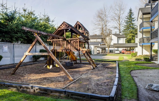 a swing set in a park with a building in the background