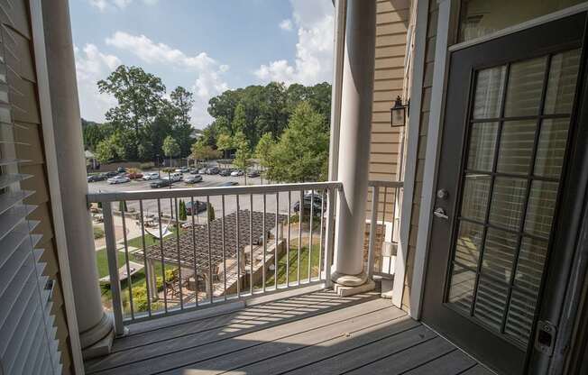 A balcony with a view of a parking lot and trees.