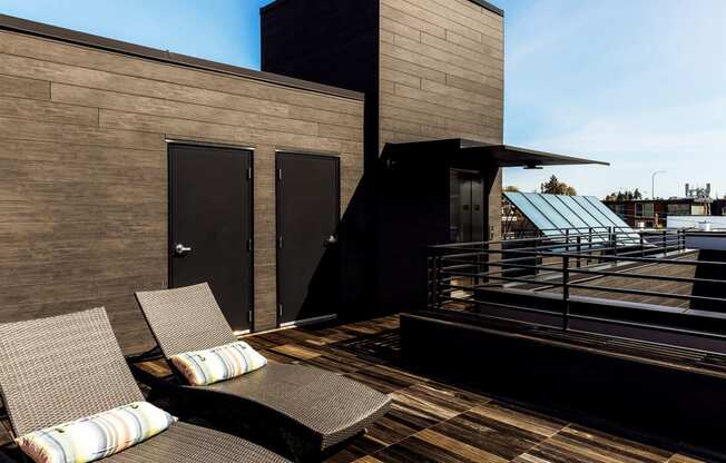 a roof deck with two chairs and a view of a building
