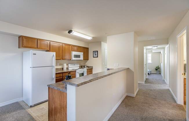 our apartments offer a spacious kitchen with stainless steel appliances and wood cabinets. large kitchen with white fridge