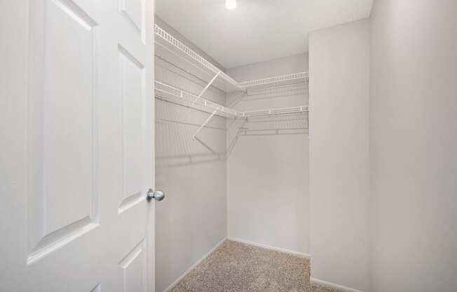 an empty closet with white walls and a white door