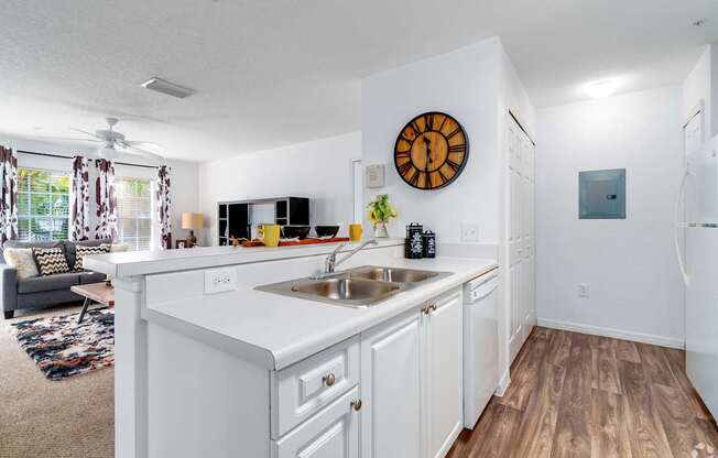 A kitchen with white cabinets and a wooden floor.