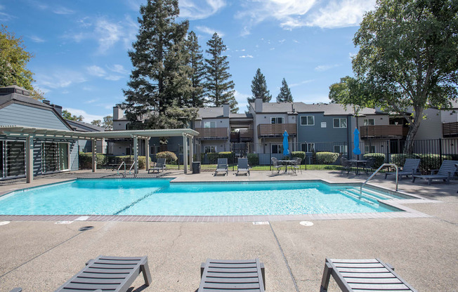 A large swimming pool surrounded by lounge chairs and trees at Sierra Glen Apartments, California, 95621
