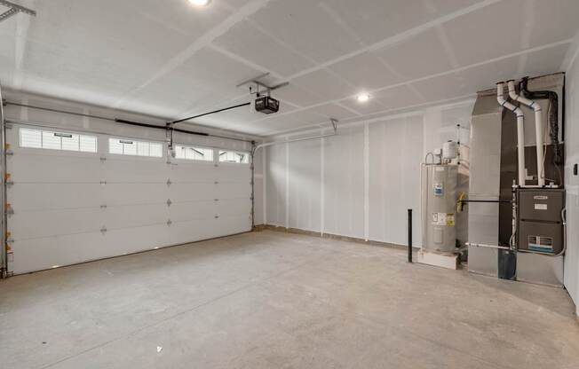 A large, empty room with a garage door on the left and a furnace on the right.