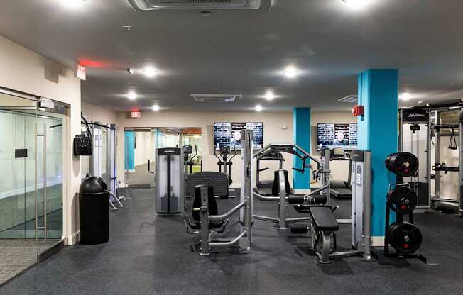 a gym with cardio machines and weights on the floor and a glass wall