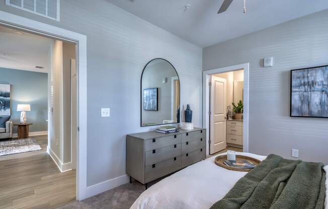 A bedroom with a large bed and a dresser with a mirror above it.