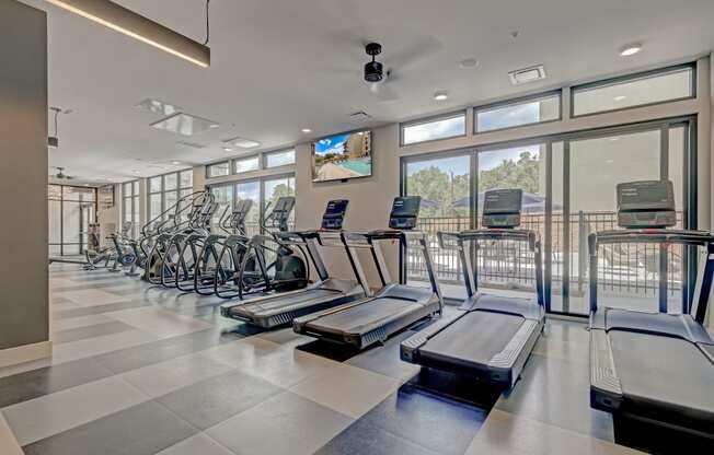 a large fitness room with cardio machines and a flat screen tv