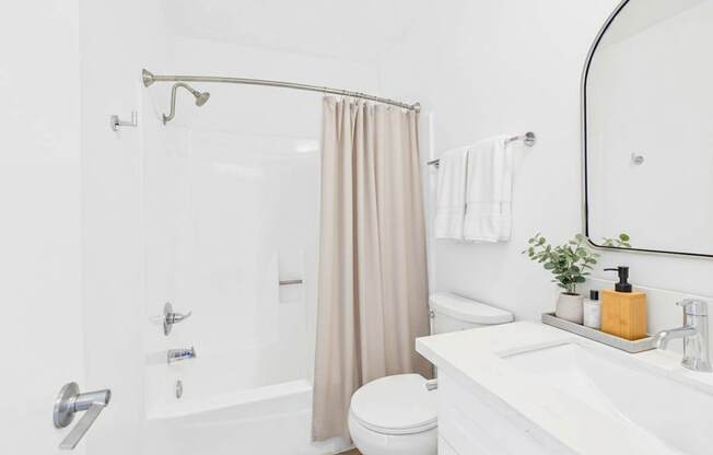 A white bathroom with a toilet, sink, and shower.
