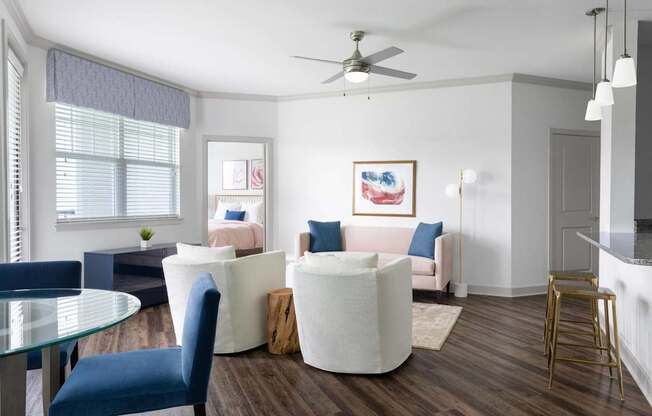A living room with a white couch, blue chairs, and a ceiling fan.