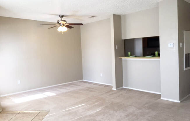 A room with a ceiling fan and a kitchenette.