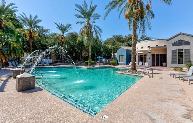 A pool with a waterfall and palm trees in the background.