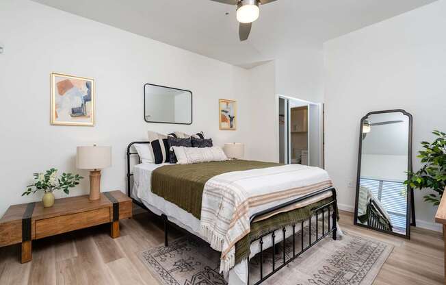 A bedroom with a bed, a nightstand, and a ceiling fan.