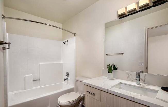 A white bathroom with a toilet, sink, and bathtub.